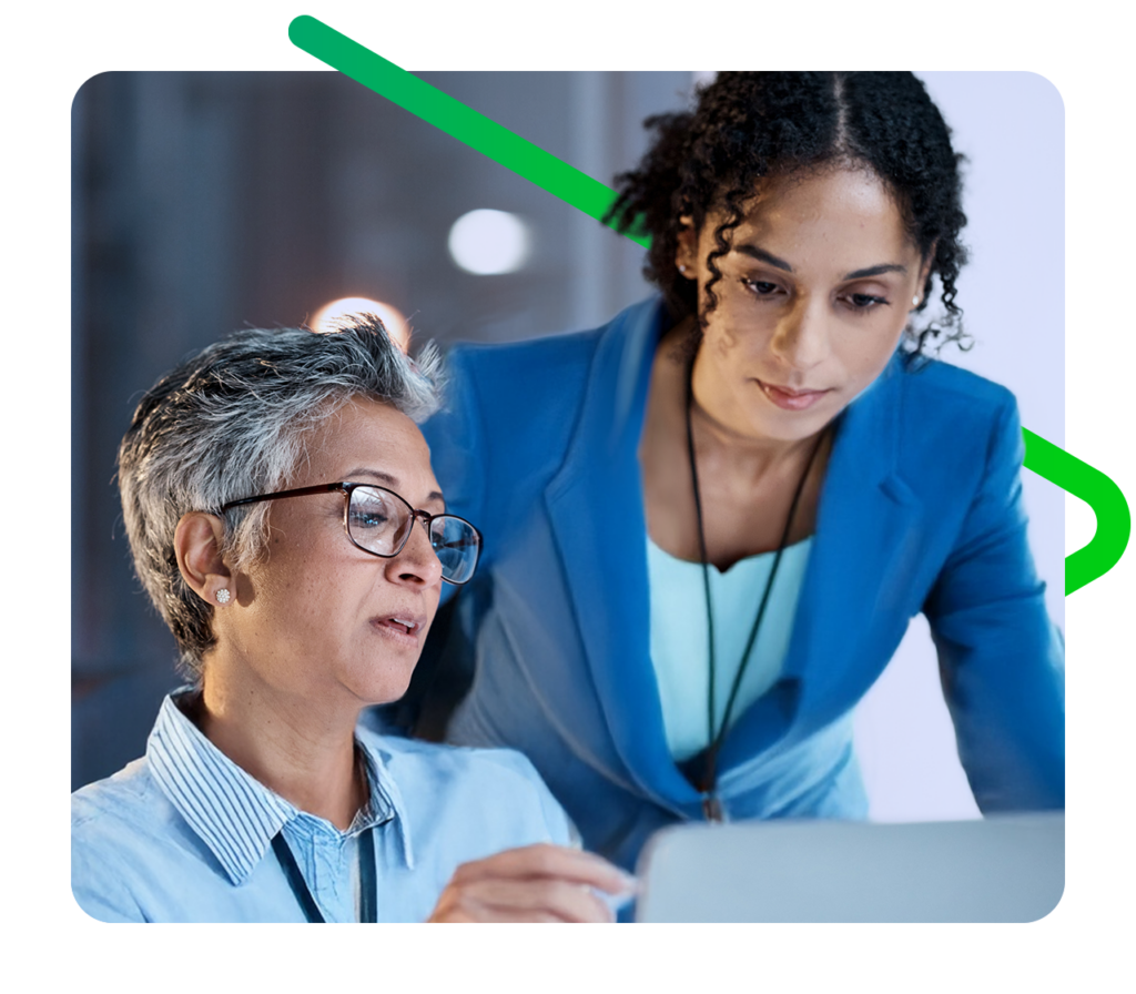 Business women look at a screen together.