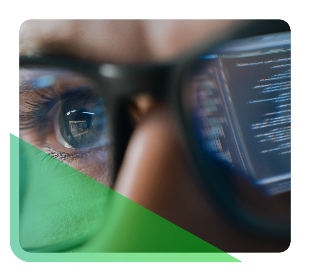 Up-close view of a man's eyes, with a computer screen reflected in his glasses.