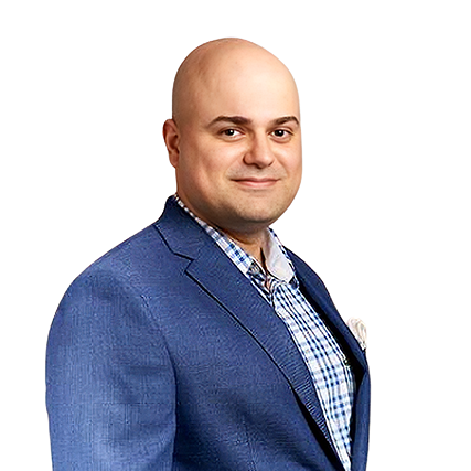 Wael Salloum, Ensemble's Chief AI Officer, dressed in a blue blazer and checked shirt, stands against a plain light background.