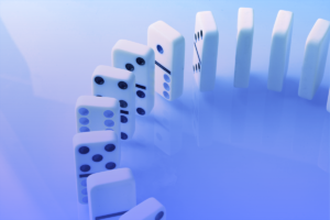Several white dominoes with black dots are arranged in a curved line, standing upright on a reflective surface with a blue-purple gradient background.
